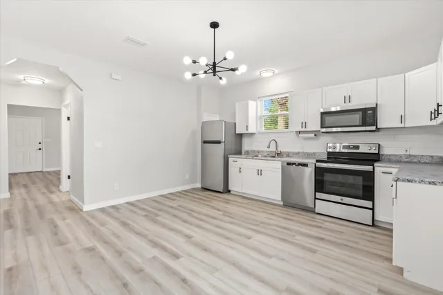 a kitchen with granite countertop a sink cabinets stainless steel appliances and a window