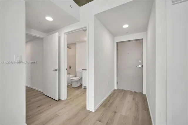 a view of a hallway with wooden floor and a bathroom