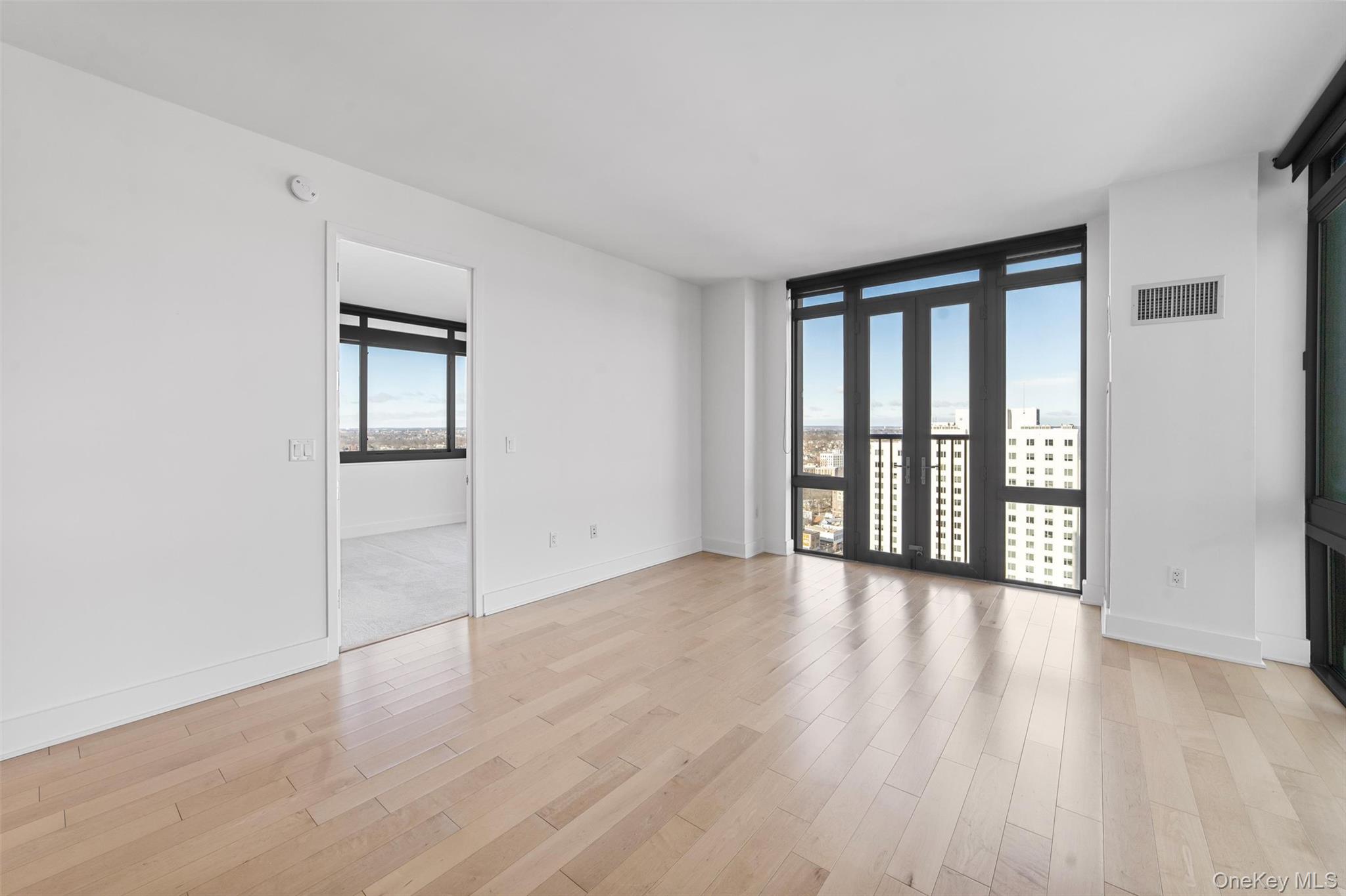 175 Huguenot Street, Unit 2108 New Rochelle, NY 10801 - Photo 7 of 18 an empty room with wooden floor and windows