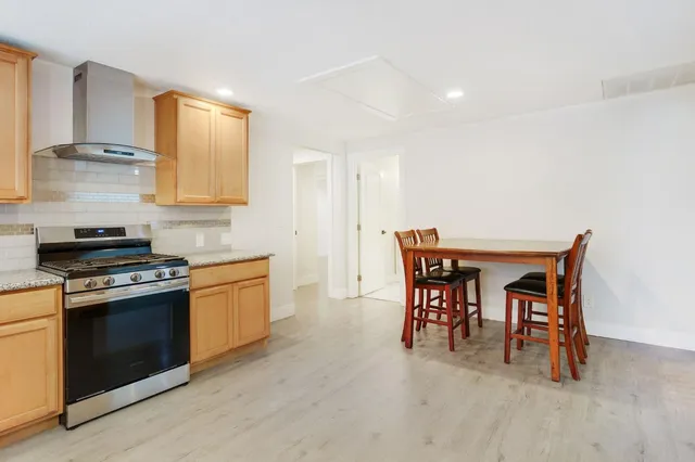 a kitchen with stainless steel appliances granite countertop a stove a sink a refrigerator and a dining table