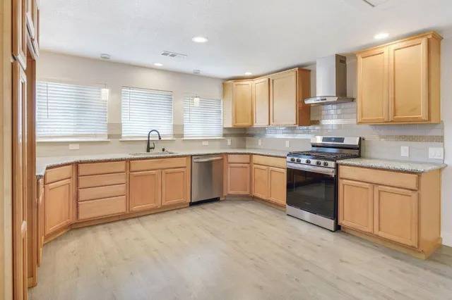 a kitchen with stainless steel appliances granite countertop a sink dishwasher stove and cabinets