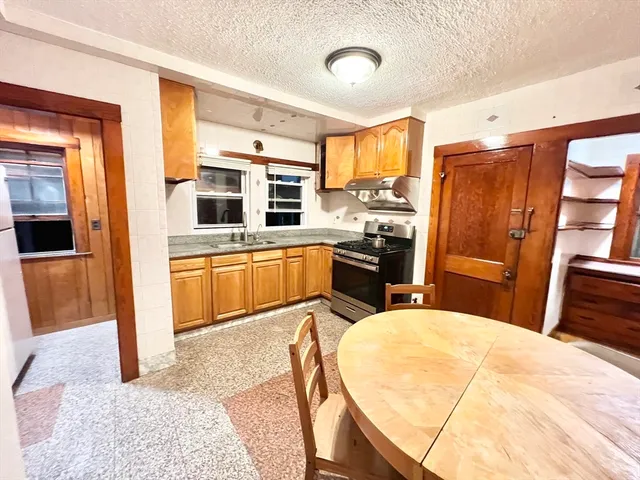 a kitchen with stainless steel appliances granite countertop a refrigerator a stove and a sink with wooden floor