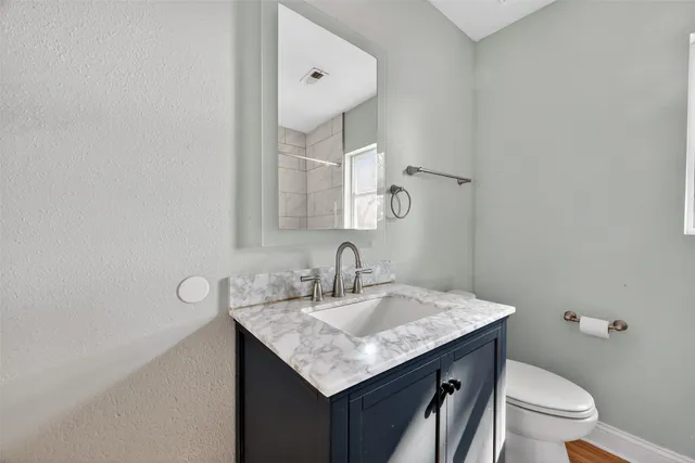 a bathroom with a granite countertop sink and a toilet