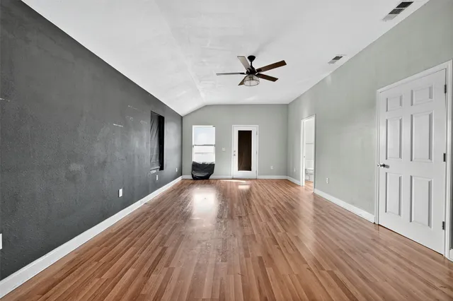 a view of empty room with wooden floor and fan