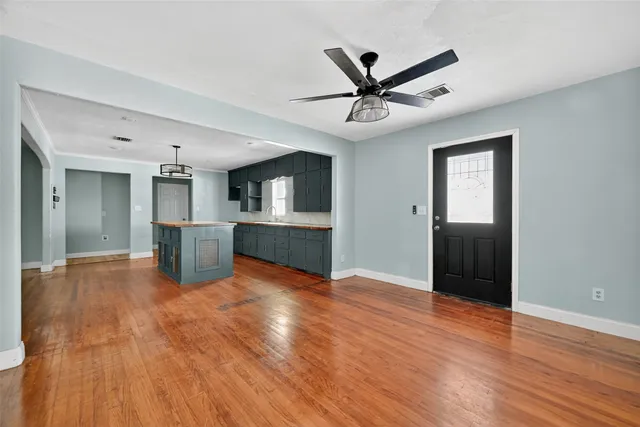 a view of a livingroom with a hardwood floor a ceiling fan and kitchen space