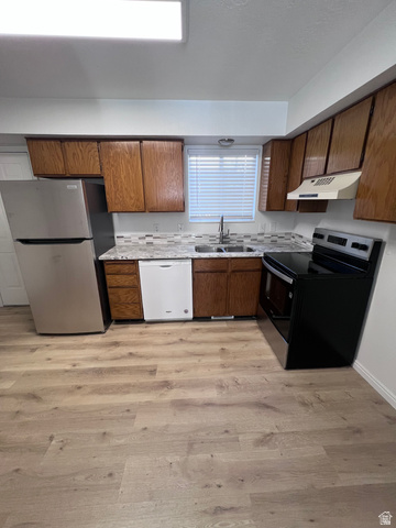 556 North Fairfield Road, Unit D4 Layton, UT 84041 - Photo 14 of 23 Kitchen with appliances with stainless steel finishes, light countertops, light wood-style flooring, brown cabinets, and under cabinet range hood