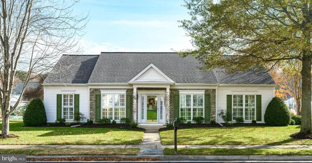 a view of a brick house with a big yard and large trees
