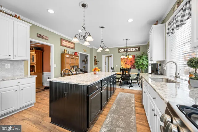 a large kitchen with kitchen island a sink a counter top space a large window and stainless steel appliances
