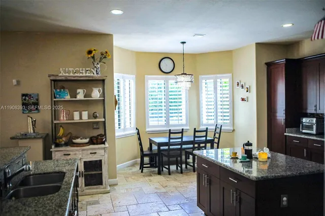 a dining hall with stainless steel appliances granite countertop a stove and a sink
