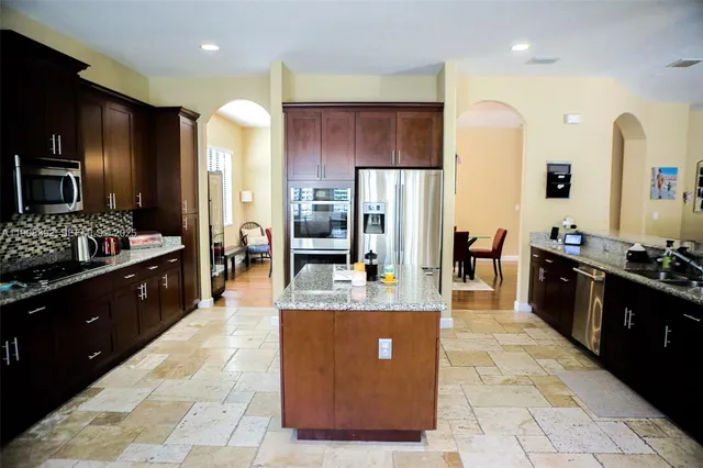 a large kitchen with stainless steel appliances kitchen island granite countertop a large counter top cabinets and refrigerator