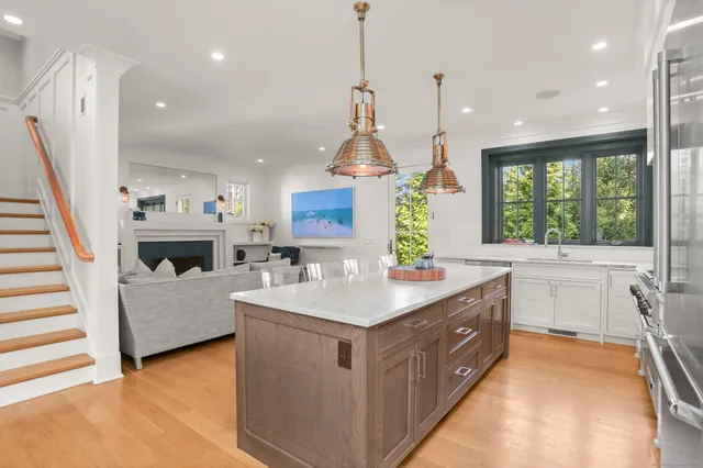 a kitchen with kitchen island a counter top space a sink a stove and a chandelier