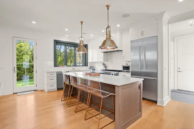 a kitchen with kitchen island granite countertop a sink a stove and a wooden floors