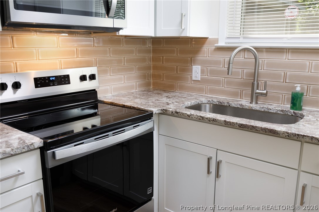 201 Scarborough Street Spring Lake, NC 28390 - Photo 9 of 26 a kitchen with granite countertop a stove and a sink