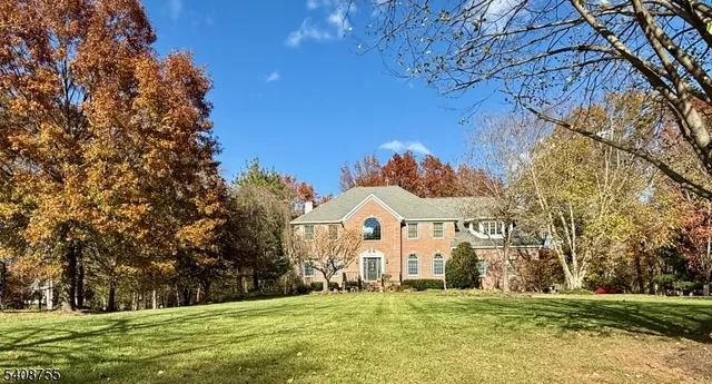 a view of a white house with a big yard and large trees