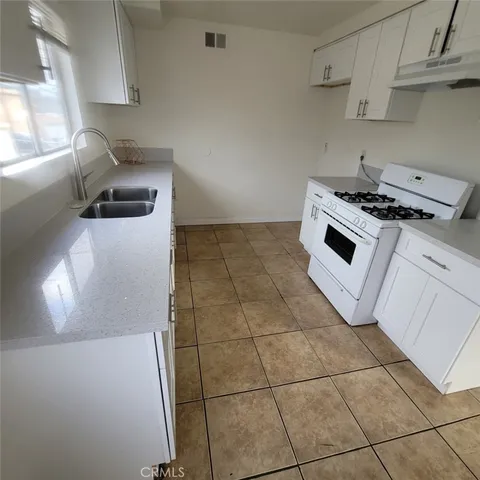 a kitchen with granite countertop a stove a sink and a refrigerator