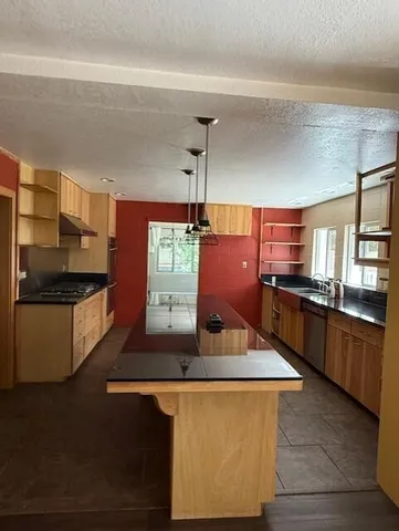 a kitchen with stainless steel appliances kitchen island granite countertop a stove a sink and a refrigerator