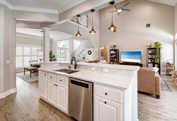 a kitchen with a sink dishwasher and white cabinets with wooden floor