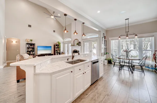 a kitchen with stainless steel appliances kitchen island granite countertop a stove a sink a refrigerator and white cabinets with wooden floor
