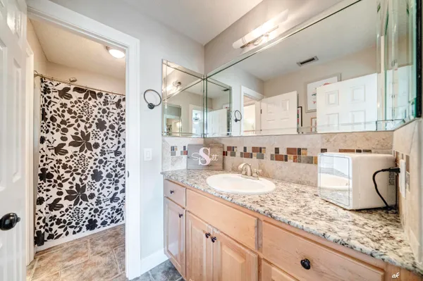 a bathroom with a granite countertop sink a mirror and a shower