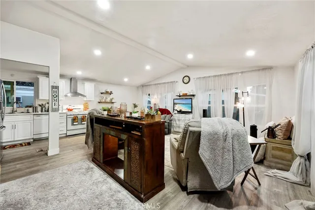 a living room with stainless steel appliances kitchen island granite countertop furniture wooden floor and a kitchen view