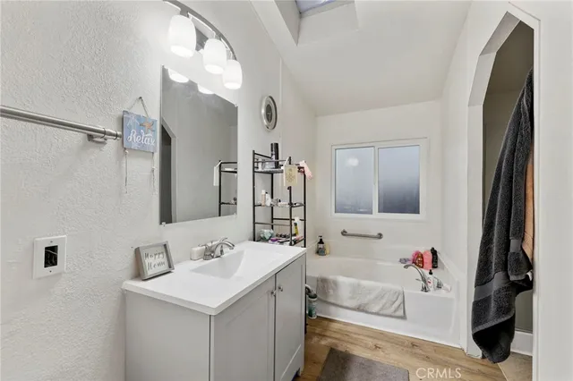 a bathroom with a sink vanity tub and a mirror