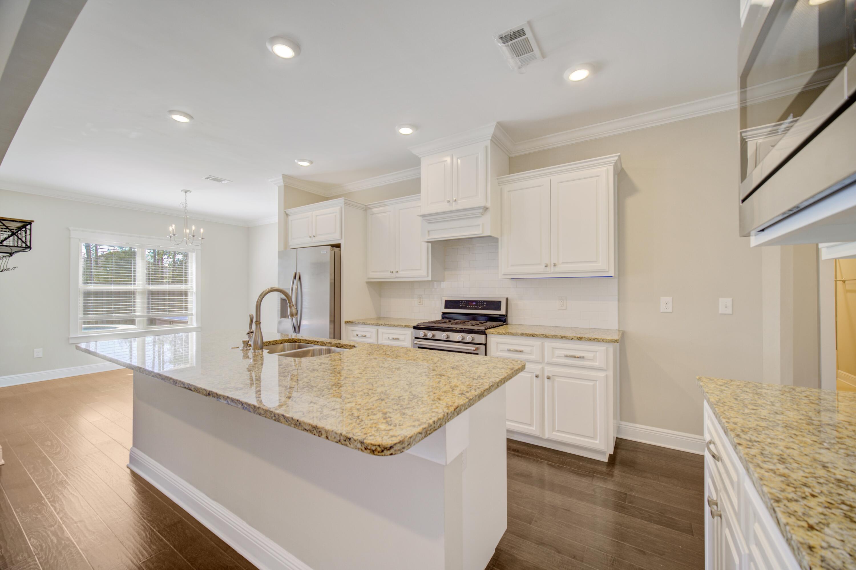136 Buxtons Way Freeport, FL 32439 - Photo 13 of 59 a large kitchen with stainless steel appliances granite countertop a stove a sink a refrigerator and white cabinets with wooden floor