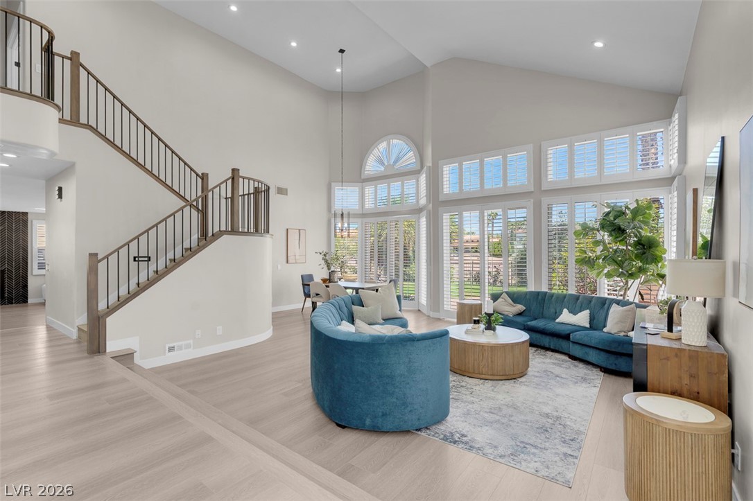 8848 Rainbow Ridge Drive Las Vegas, NV 89117 - Photo 6 of 43 Natural light floods this living room, featuring soaring ceilings and hardwood flooring, creating an inviting atmosphere.