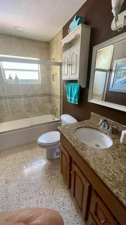 a bathroom with a granite countertop sink a toilet a mirror and shower