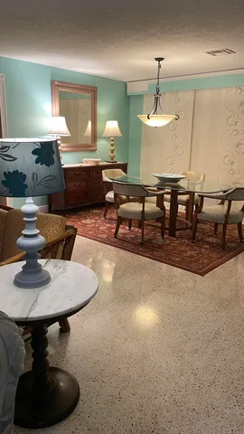 a living room with dining table and a chandelier