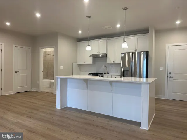 a large kitchen with stainless steel appliances a refrigerator and a stove top oven