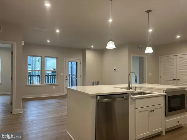 a kitchen with a sink chandelier and wooden floor