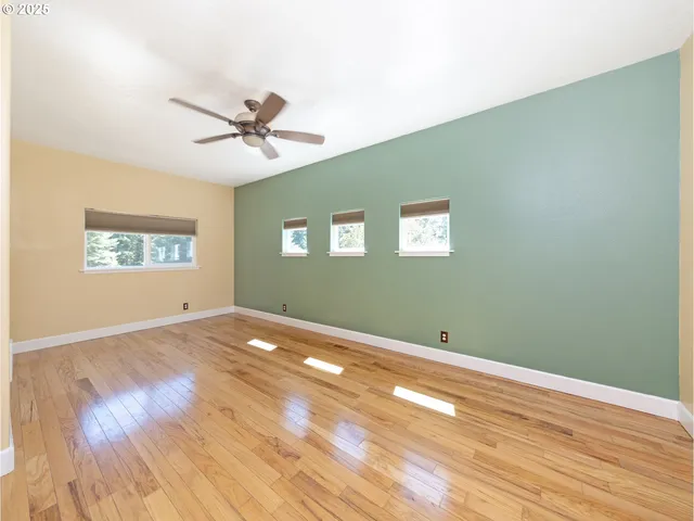 a view of empty room with wooden floor and fan