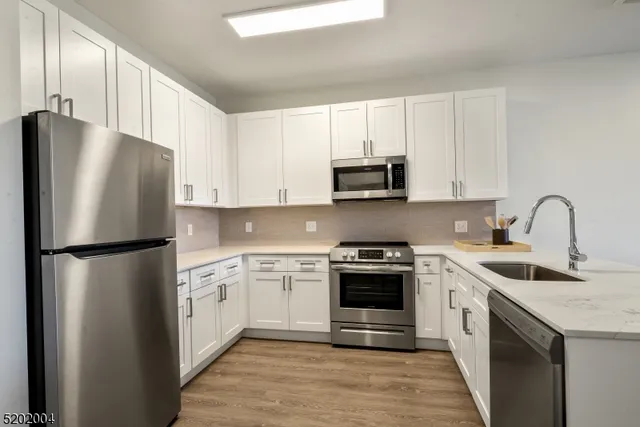 a kitchen with stainless steel appliances a refrigerator stove and white cabinets
