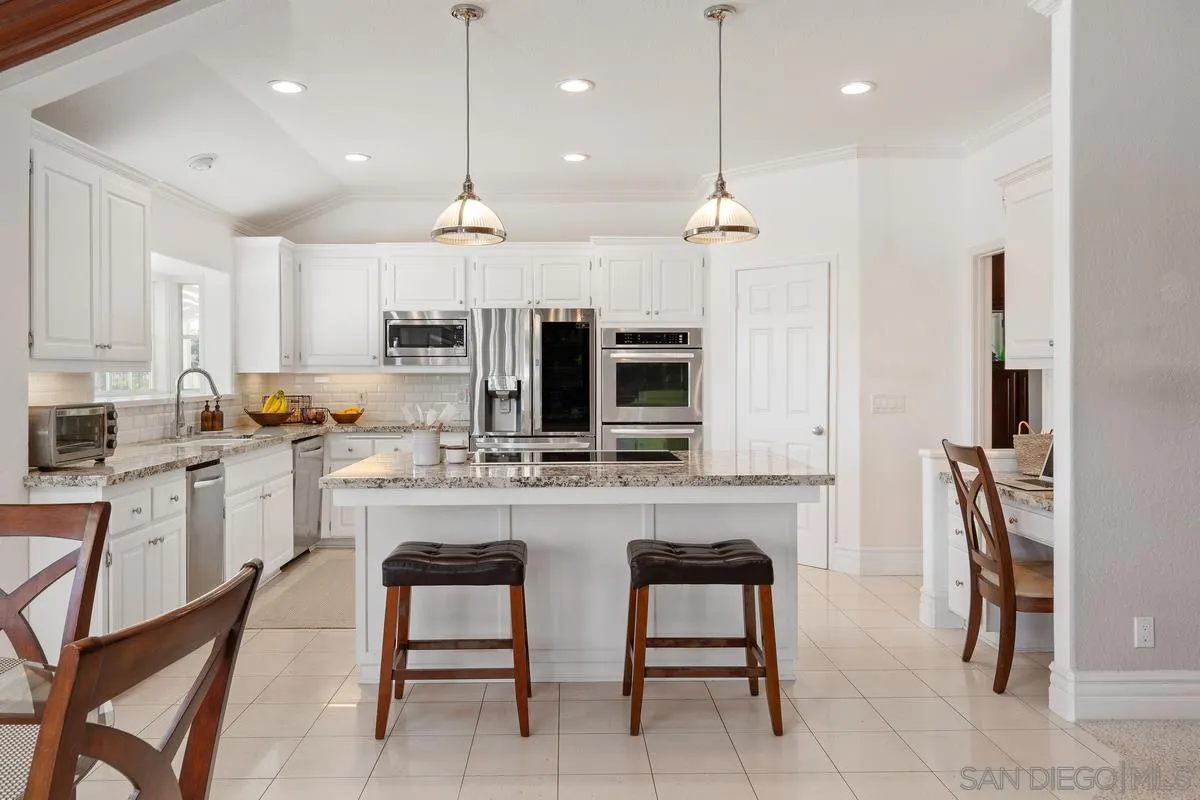 14134 Palisades Drive Poway, CA 92064 - Photo 13 of 32 a kitchen with kitchen island granite countertop a stove a sink a oven a kitchen island with a dining table and chairs