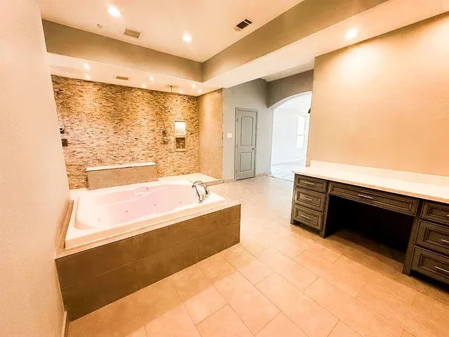 a spacious bathroom with a tub sink and mirror