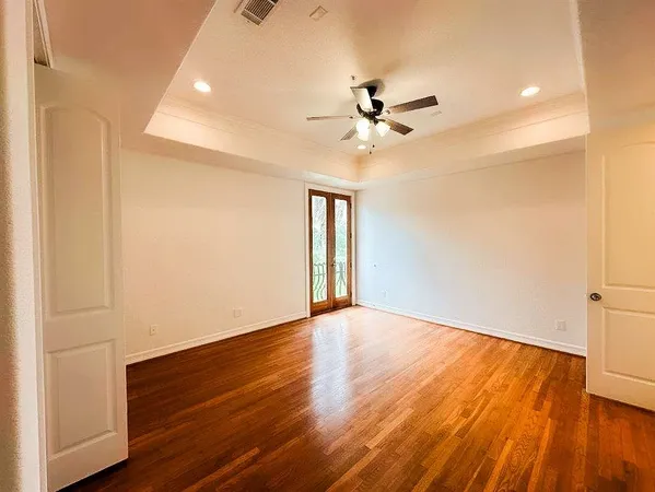 a view of empty room with wooden floor and fan