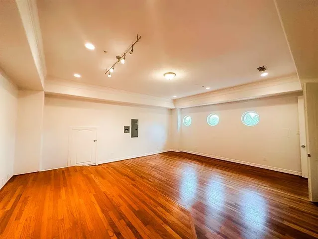 an empty room with wooden floor and windows