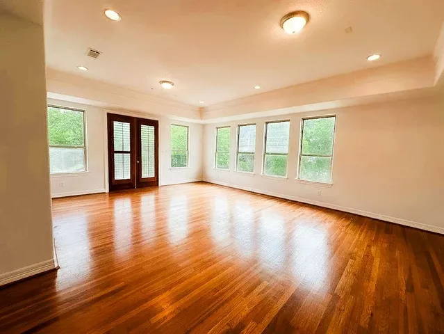 a view of empty room with wooden floor and ceiling fan