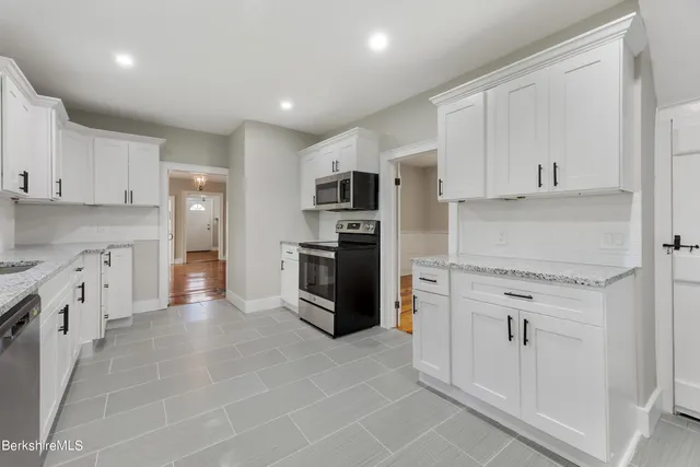 a kitchen with granite countertop white cabinets and stainless steel appliances