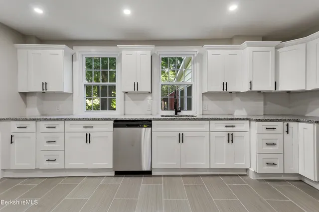 a kitchen with granite countertop white cabinets stainless steel appliances a sink and a window