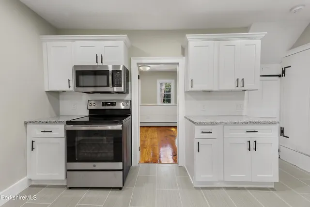 a kitchen with white cabinets and stainless steel appliances