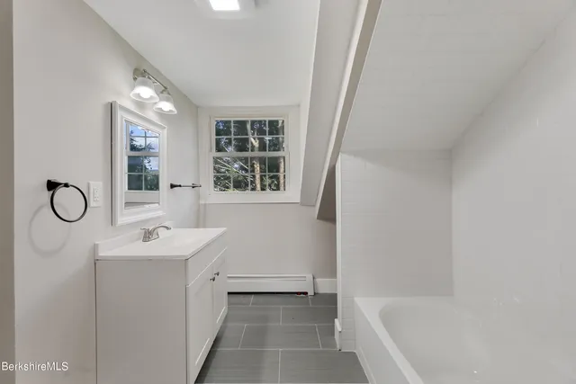 a bathroom with a tub sink and mirror
