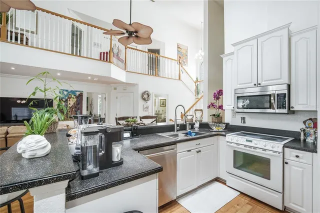 a kitchen with a sink dishwasher a stove top oven a dining table and chairs with wooden floor