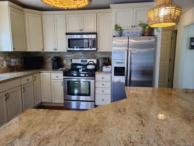 a kitchen with stainless steel appliances granite countertop a stove refrigerator and a microwave
