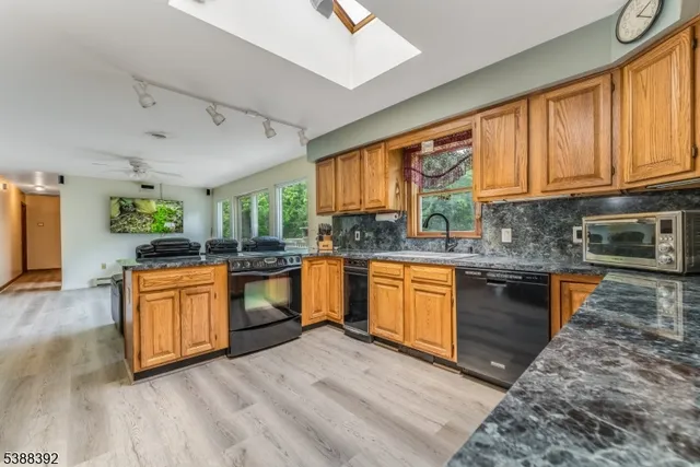 a kitchen with granite countertop wooden floors stainless steel appliances and window