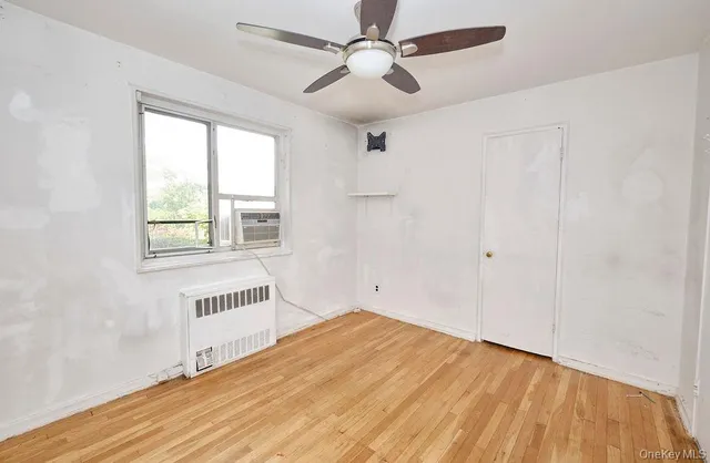 a view of an empty room with a window and wooden floor