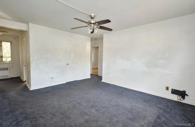 an empty room with a ceiling fan and a window