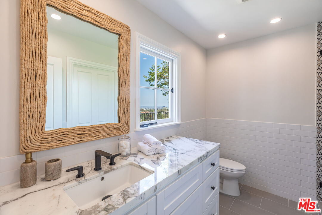 1756 Correa Way Los Angeles, CA 90049 - Photo 25 of 38 a bathroom with a granite countertop sink a toilet and a mirror