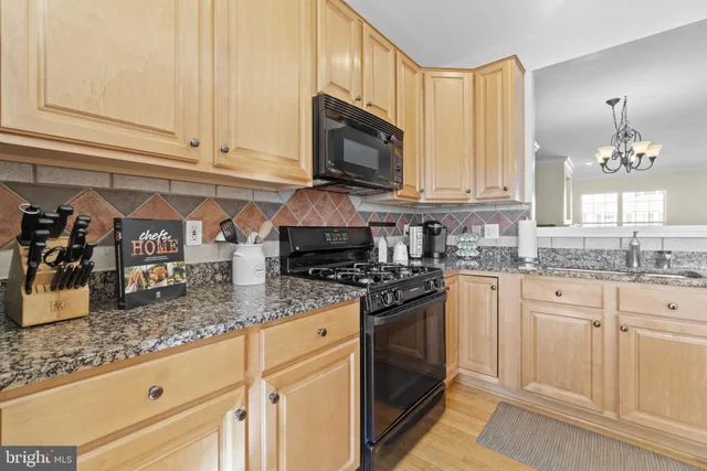 a kitchen with granite countertop a sink a stove and cabinets