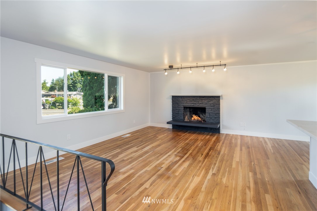 16504 124th Avenue Southeast Renton, WA 98058 - Photo 5 of 29 a view of an empty room with wooden floor fireplace and a window